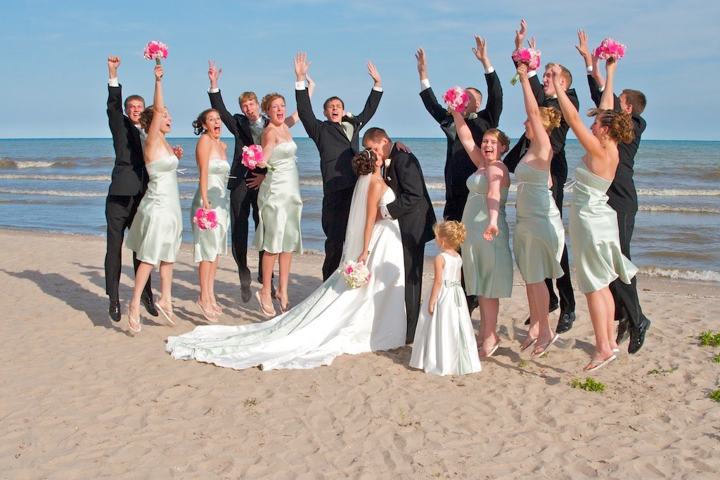 Bride and Groom taking their wedding day portraits with their Wedding Party on the Beach Jumping