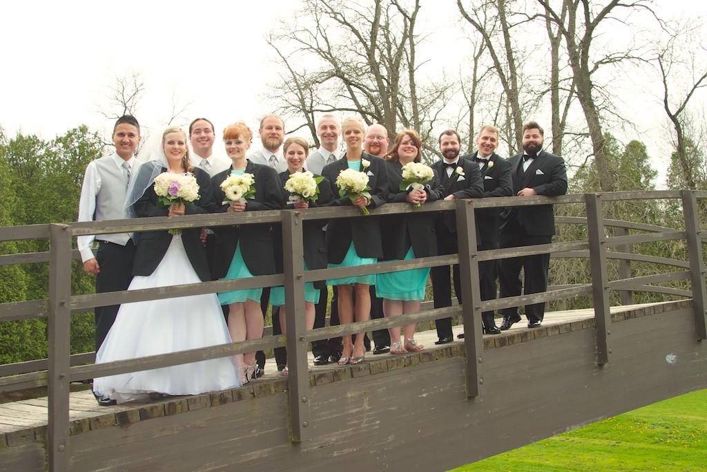 Groom and Bride with their Wedding Party on a Bridge in Evergreen Park, Sheboygan, WI Holding Flowers for their wedding day portraits