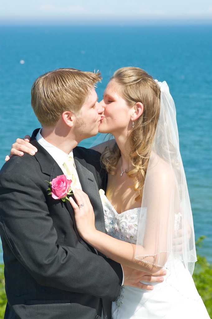 Groom Kissing Bride on the shore of Lake Michigan in Sheboygan, WI for their Wedding Day Portraits