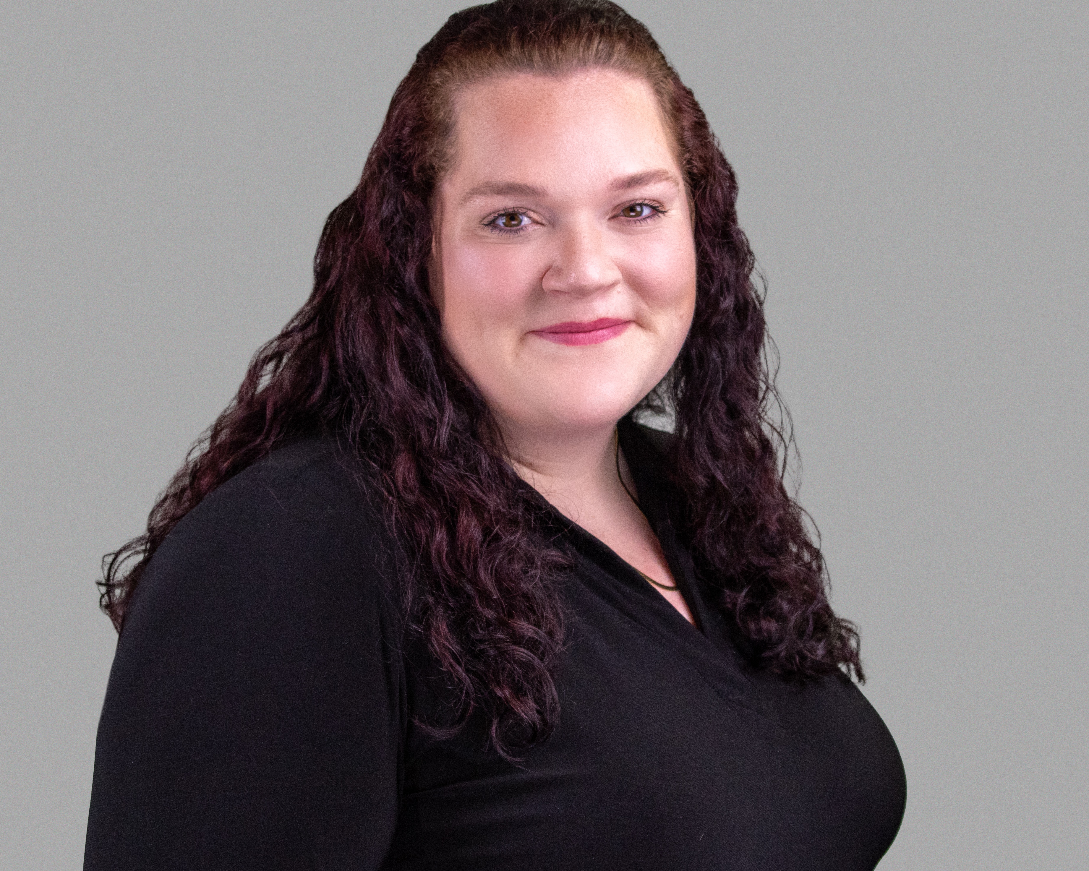 Studio Headshot, woman in black top, grey background